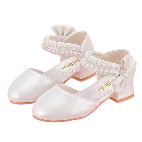 Białe perłowe pantofelki komunijne dla dziewczynki z ozdobnymi paskami z perełek oraz dużą kokardą na pięcie.