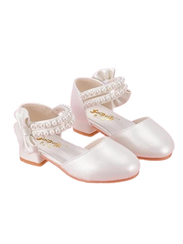Białe perłowe pantofelki komunijne dla dziewczynki z ozdobnymi paskami z perełek oraz dużą kokardą na pięcie.