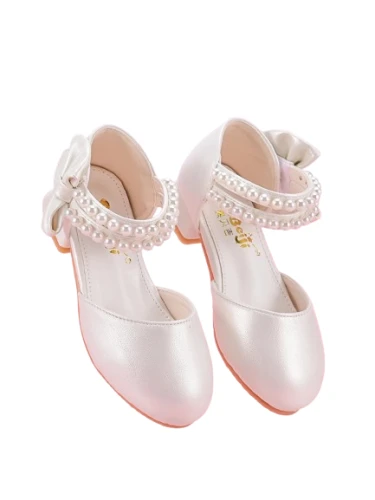 Białe perłowe pantofelki komunijne dla dziewczynki z ozdobnymi paskami z perełek oraz dużą kokardą na pięcie.