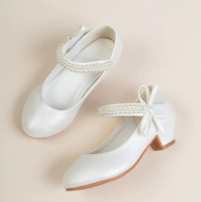 Eleganckie białe pantofelki komunijne dla dziewczynki z perłowym połyskiem, paskami z perełek i ozdobną kokardą.