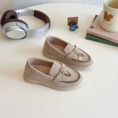 Zamszowe mokasyny dziecięce z ozdobnym złotym elementem, dostępne w kolorze beżowym, granatowym i brązowym.