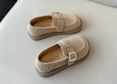 Zamszowe mokasyny dla dziewczynki z ozdobnym paskiem i prostym złotym elementem, dostępne w kolorze brązowym i beżowym.