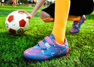 Dziecięce buty piłkarskie korki z dwoma paskami na rzepy i systemem kołków do gry na trawie.