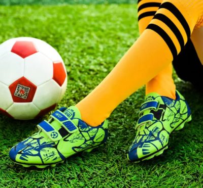 Dziecięce buty piłkarskie korki z dwoma paskami na rzepy i systemem kołków do gry na trawie.