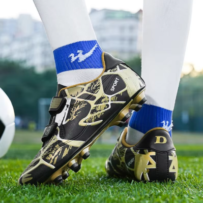 Dziecięce buty piłkarskie korki z dwoma paskami na rzepy i systemem kołków do gry na trawie.