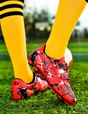 Dziecięce buty piłkarskie korki z dwoma paskami na rzepy i systemem kołków do gry na trawie.